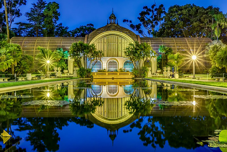 A golden lit conservatory with a pond in the foreground