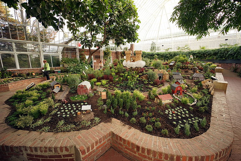 A variety of plants and flowers inside of a brick border wall