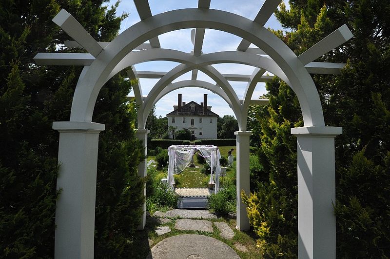 White archway leading to a white house in the distance