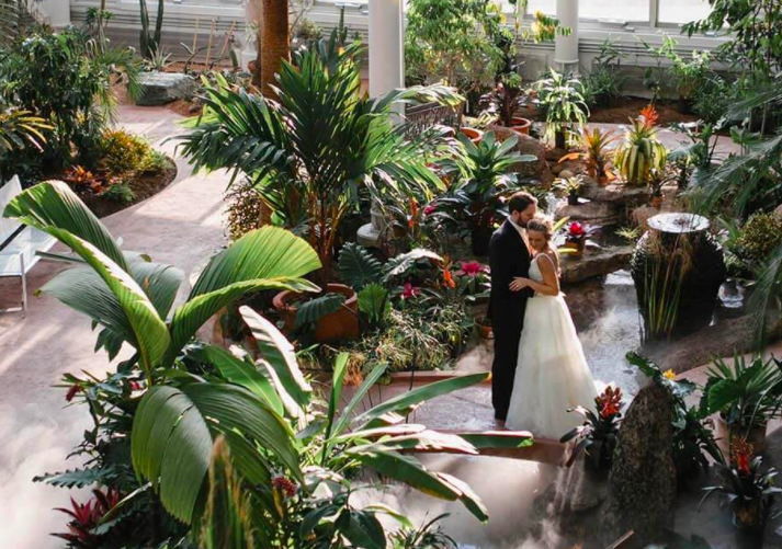 Bride and groom standing among exotic plants and flowers