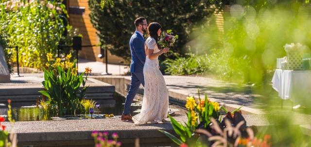 Bride and groom walking down a stone path amid flowers