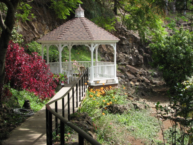 White gazebo with pathway leading up to it, surrounded by floral landscape