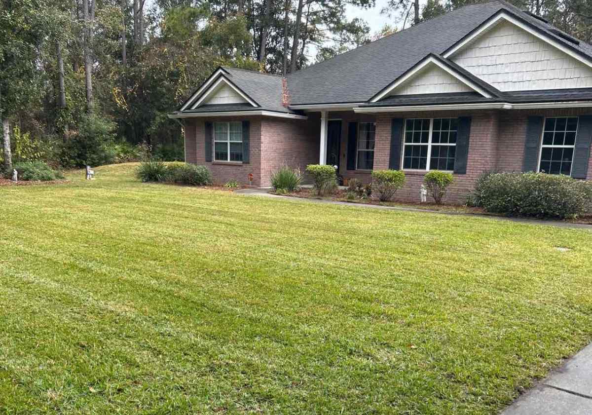 Well-maintained front lawn with neatly mowed grass in front of a brick house in Jacksonville, Florida.