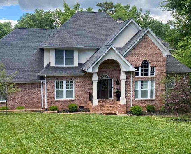 Brick house with well-maintained lawn and landscaped shrubs in a suburban Charlotte, North Carolina neighborhood.