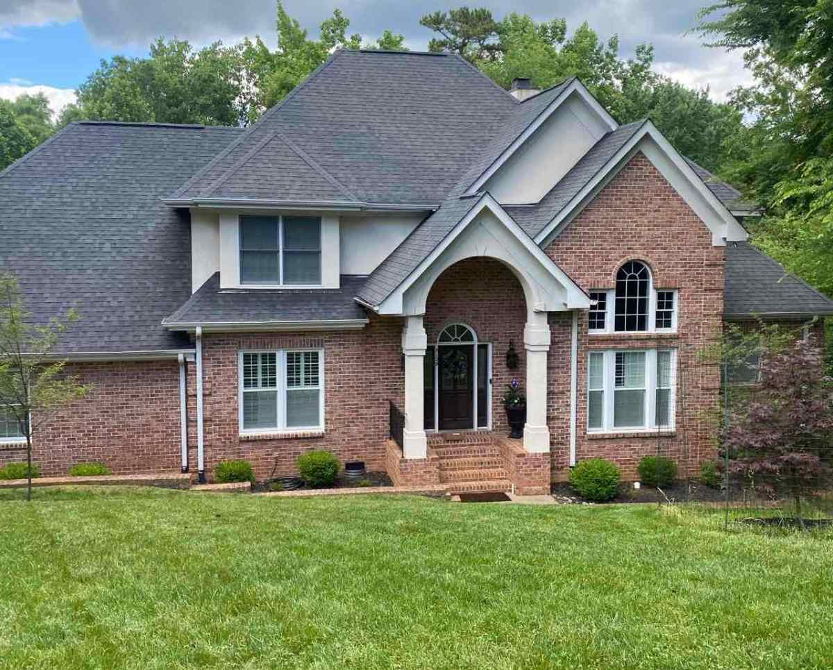 Brick house with well-maintained lawn and landscaped shrubs in a suburban Charlotte, North Carolina neighborhood.