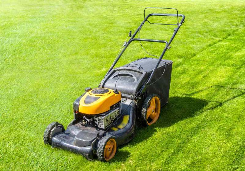 Lawn mower on fresh green lawn, freshly cut grass on summer sunny day