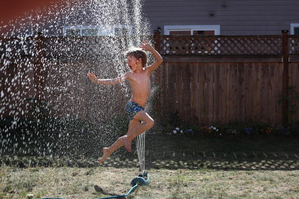 Kid playing in water sprinkler