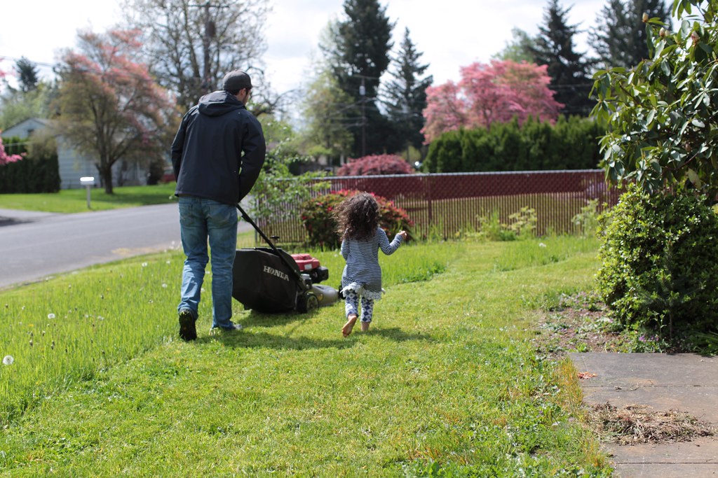 Adult and child mowing lawn