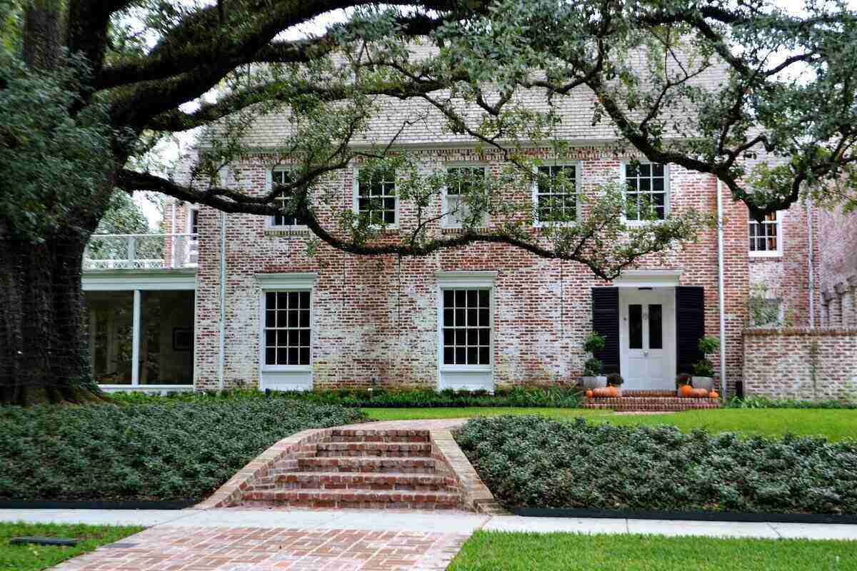 large brick house with a large tree and ground cover in the front yard