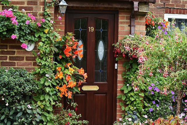 Front door with flowers and plants around it