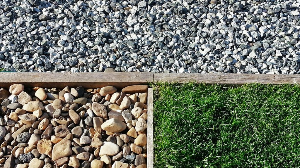 Two types of landscaping rocks with grass separated by wood planks