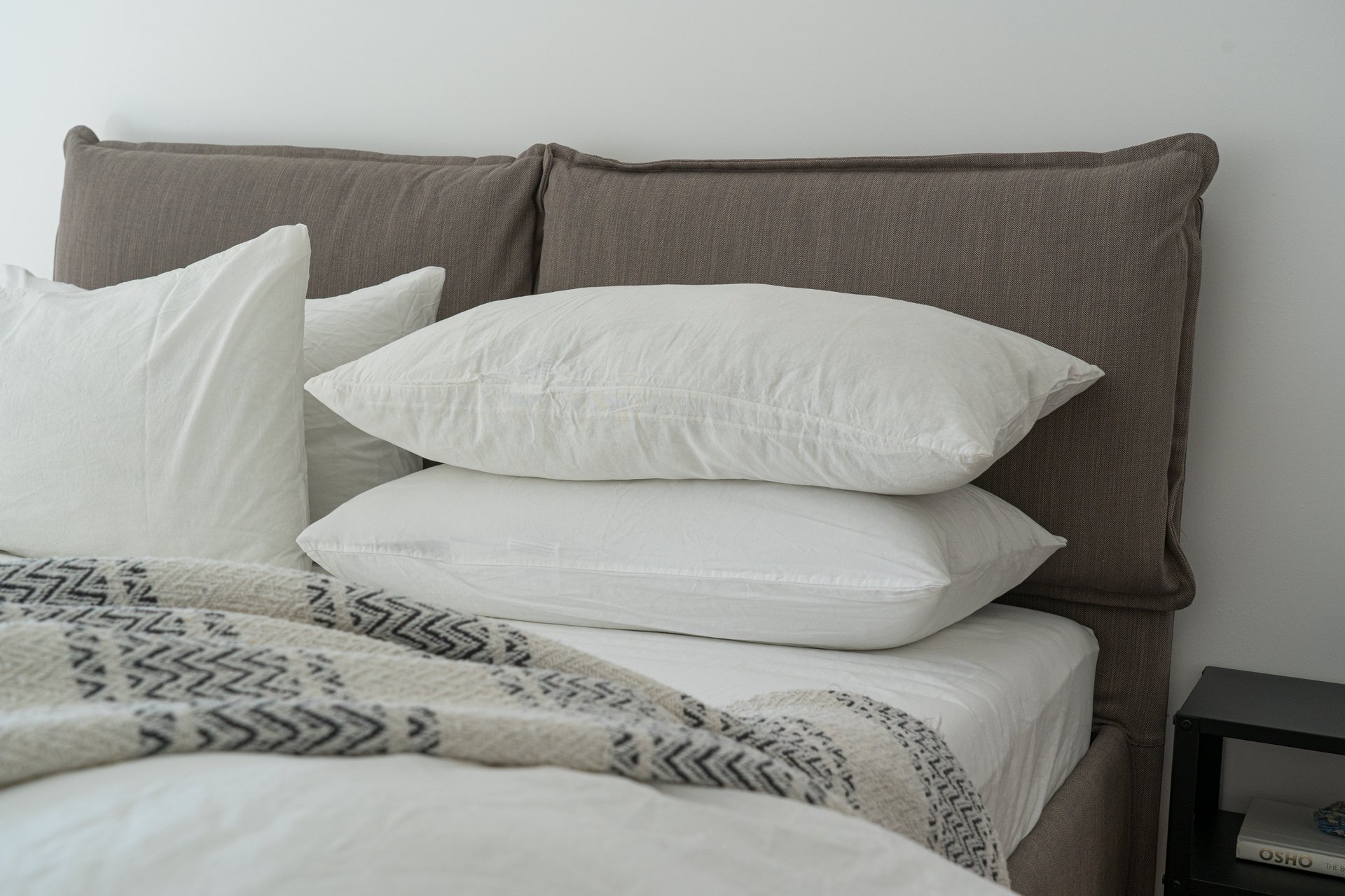 White pillows on a bed. Washing bed sheets at the highest setting is a good way to prevent bed bugs.