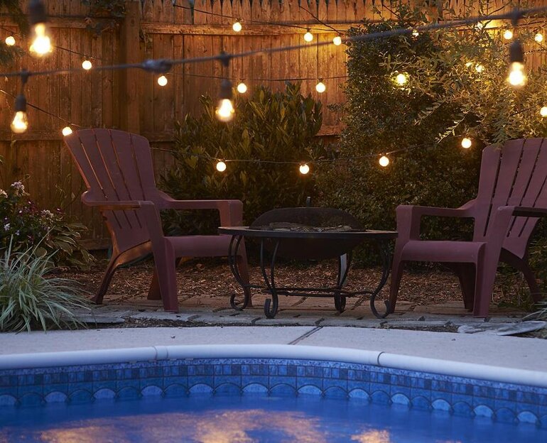 String lights hanging over a pool and seating area