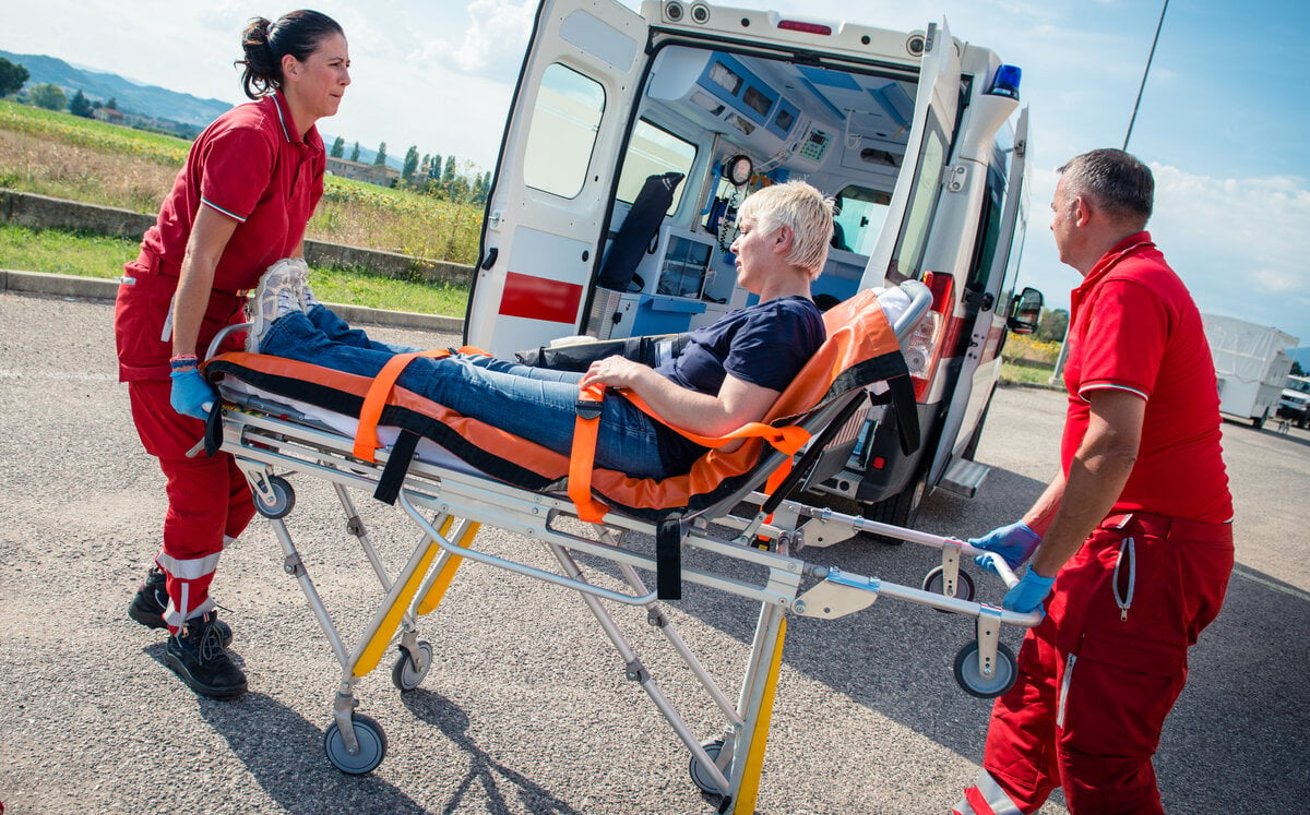 Emergency medical team members rush a patient on a stretcher to an ambulance.