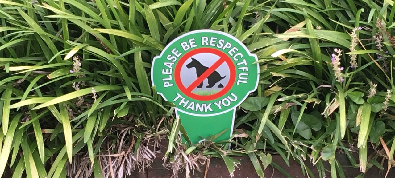 Front yard sign urging folks to pick up their dog's pet waste.