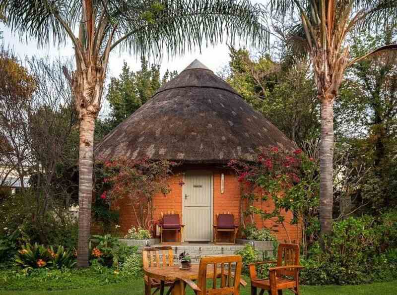 Two tall palm trees tower over a small hut near an outdoor seating area