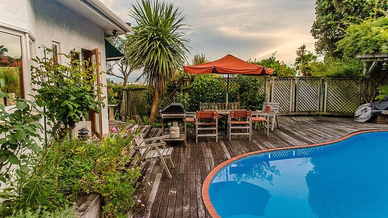 A swimming pool with a deck, fence, and lots of plants