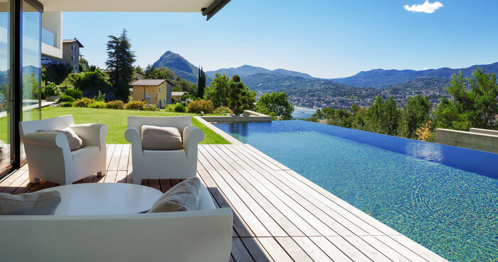 A terraced pools cape with wood patio beside pool and couches on another level