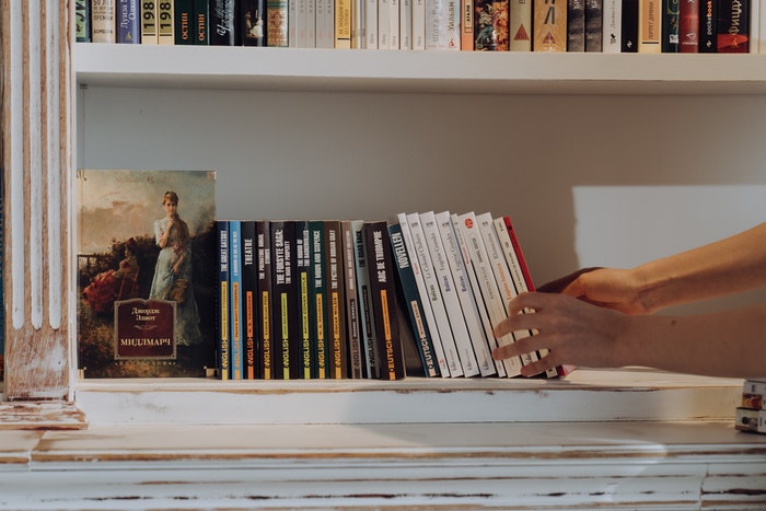 Hands putting books on a shelf