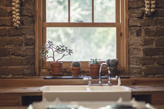 Sink by wooden window and brick wall