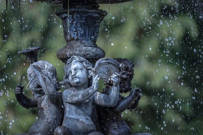 Close up of fountain with green foliage in the background