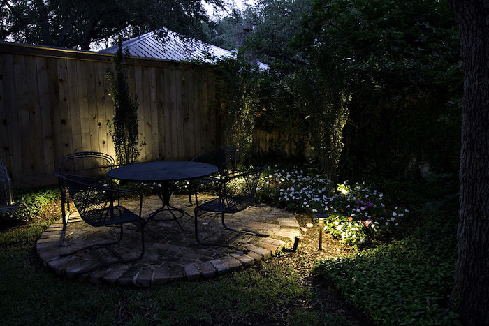 Small garden lit up by lamps at night