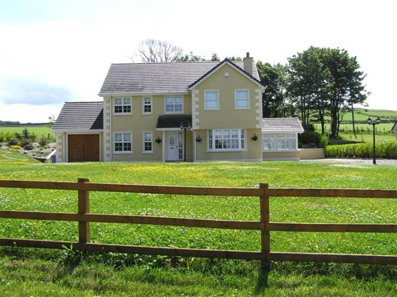 Wooden split-rail fence in front of a big green lawn and two story house