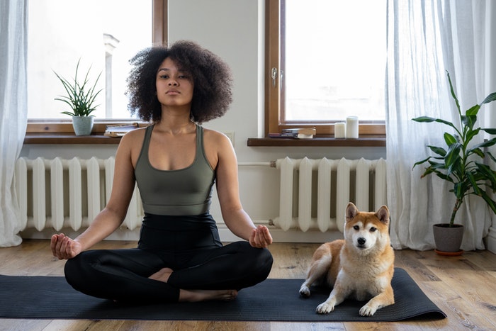 Woman meditating on yoga mat with dog