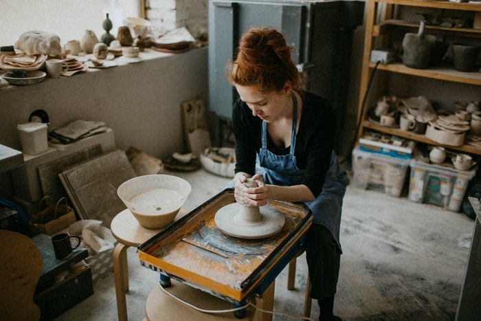 Woman works at a potter's wheel in a studio spacious enough for a she shed