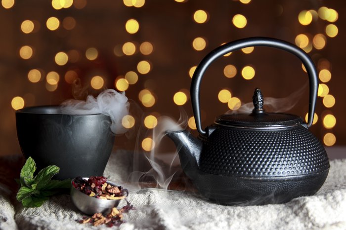 Black teacup and teapot with golden light background