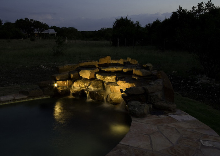 Lights shine on small stone waterfall at night