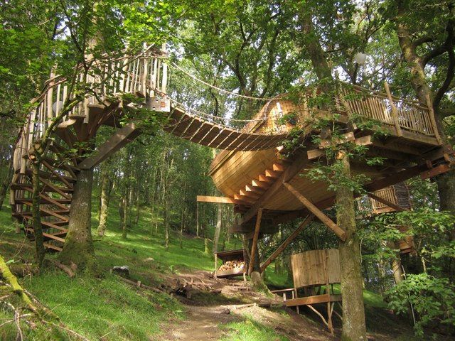 A treehouse with spiral staircase and a rope bridge