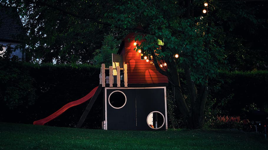 Child's playhouse at night, lit by string lights