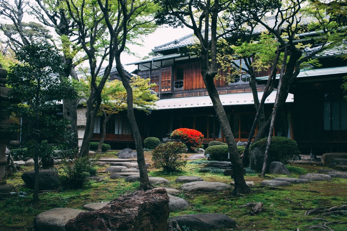 Landscaping in front of Asian-styled home with stepping stones, shrubs, and trees
