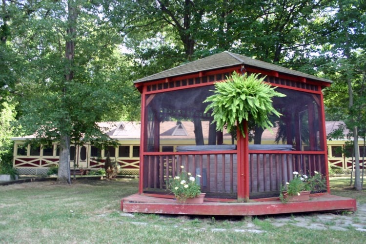Redwood backyard gazebo with hot tub inside, adorned with hanging basket and potted flowers