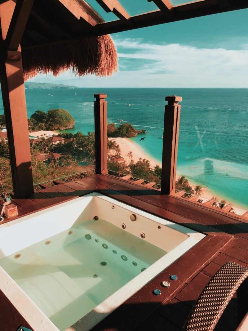 dark brown, wooden pergola overtop a hot tub with an ocean view