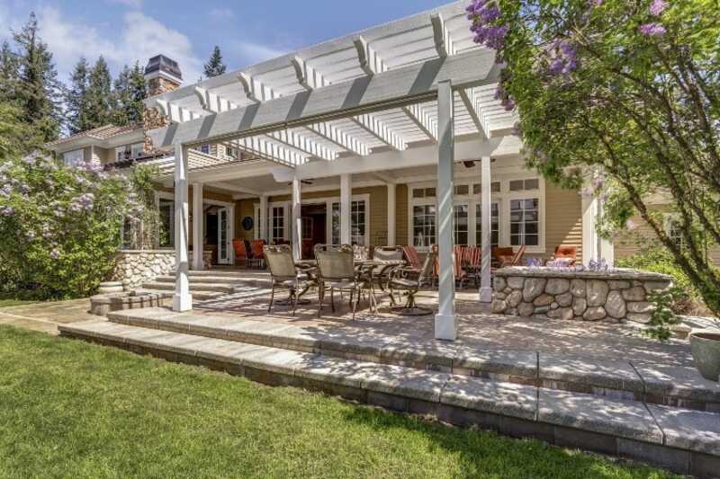 white, wooden pergola connected to exterior wall over backyard patio