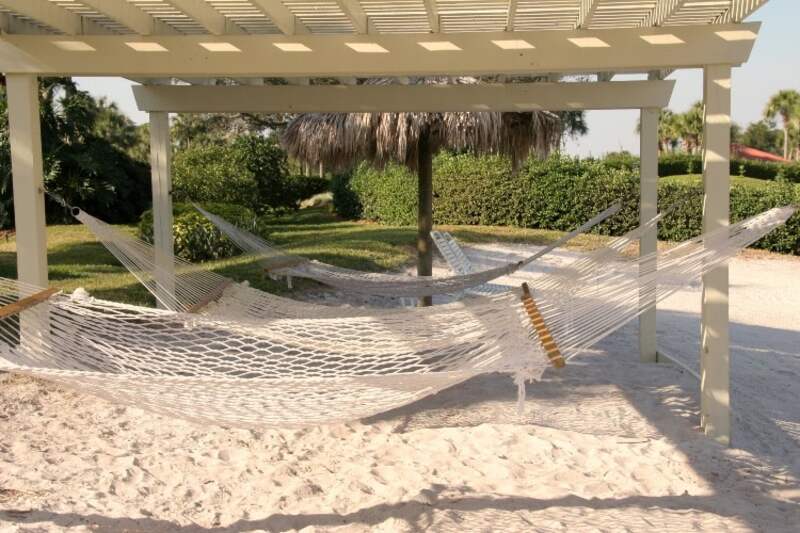 white, wooden pergola with three hammocks tied to posts