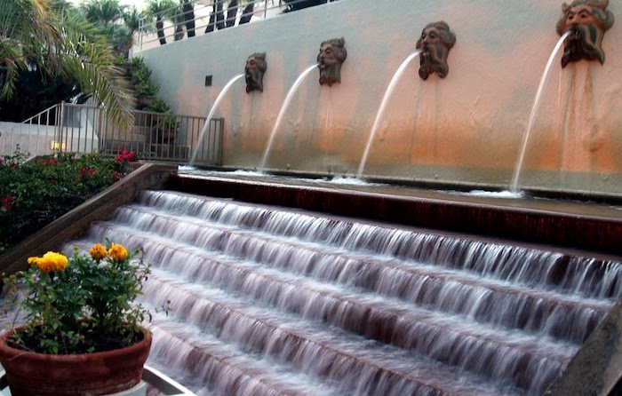 Fountain with water spilling from wall sconces onto a stairway waterfall