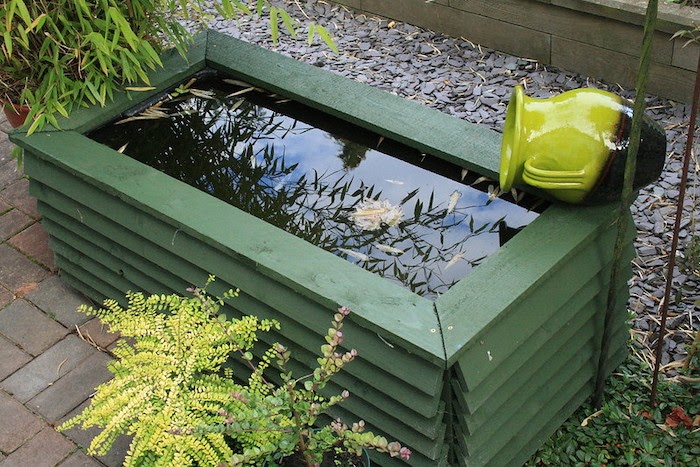 Recycled garden water feature made from a plastic container and green treated wood