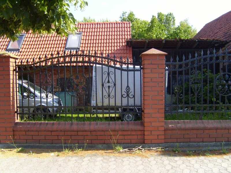 Black iron fence with brick columns, house and truck in the background
