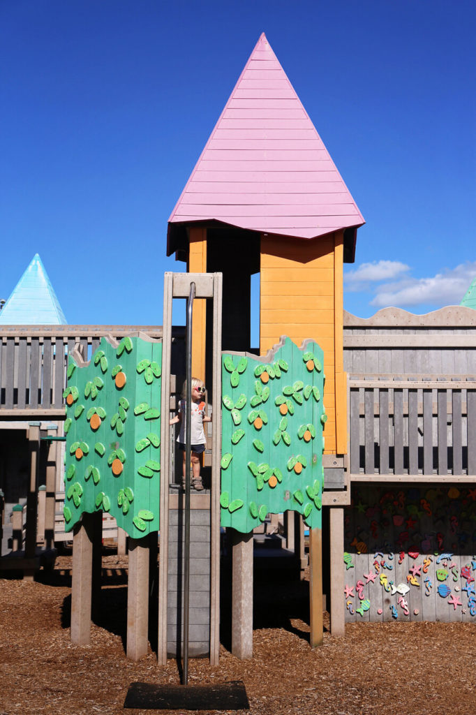 Colorful castle playground with girl waiting to use fireman's pole