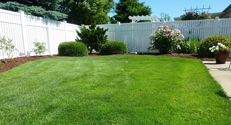 White vinyl security fence around green lawn