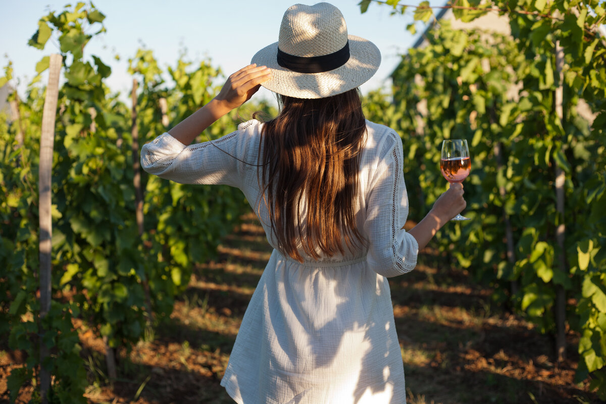 Woman walking in vineyard holding a glass of wine