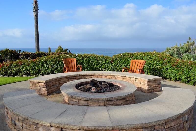 Two chairs by an outdoor fire pit against a blue sky