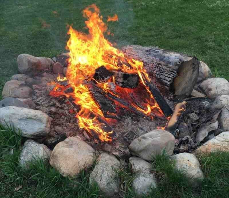 Wood-burning fire in a rock circle on grass