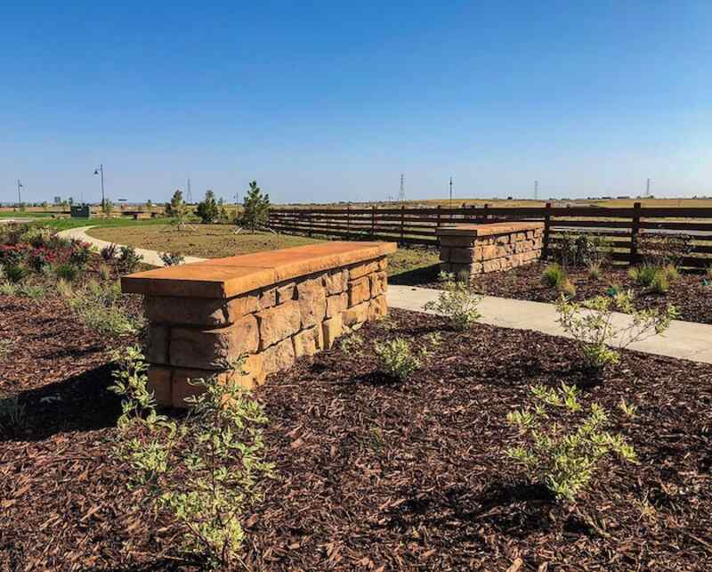 Two freestanding walls made of landscaping blocks surrounded by brown mulch and divided by path.