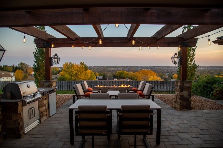 patio pergola with string lights, seating, a dining area, and an outdoor kitchen