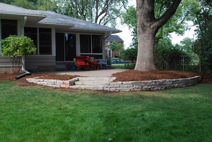 Retaining wall and mulch surround a tall tree in the landscape