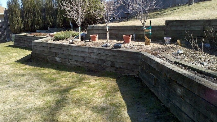 Long timber retaining wall retains soil and small trees